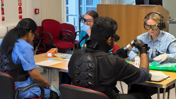 Staff sat around a table completing various daily tasks wearing different age simulation equipment