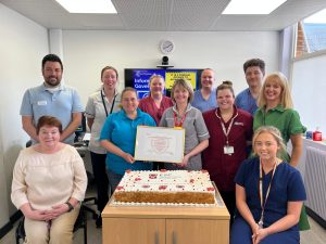 Staff pose with cake to celebrate their success