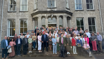 Large group of people posing for a photo on the steps of a stone building.