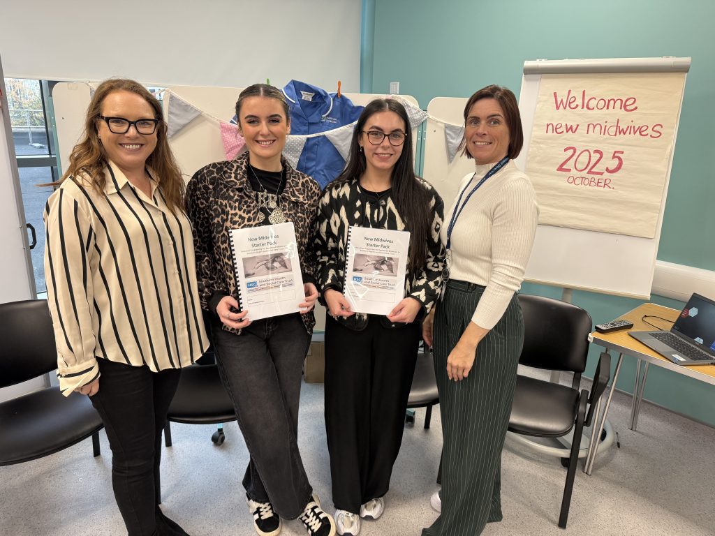 four woman standing and one holding a booklet