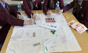 A group of students creating a design on a page in the centre of the table.