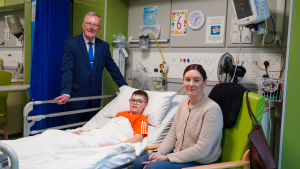 Health Minister Mike Nesbitt stands beside the bed of a patient and family member in Daisy Hill Hospital
